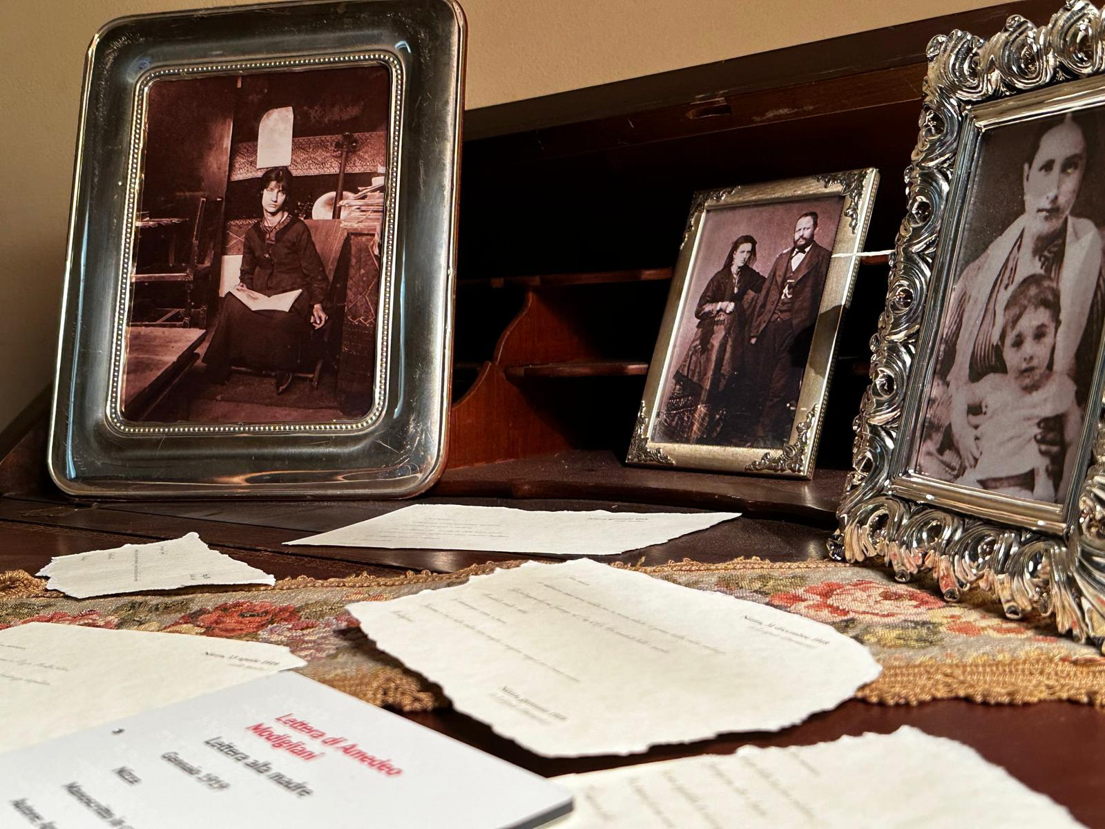 Fotografie storiche incorniciate e lettere esposte su uno scrittoio